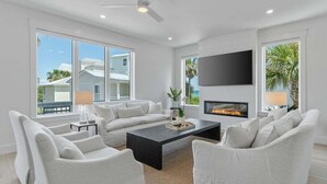 A modern living room with a fireplace, white furniture, and large windows.