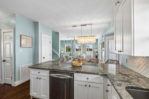 A kitchen with white cabinets, a granite countertop, and a stainless steel dishwasher.