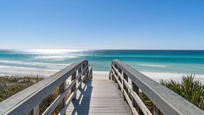A wooden boardwalk leading to a beach with clear blue water and a sandy shore. - Ocean front: Private Pool + Private Beach Access (Seagrove Beach)