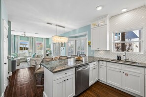 A modern kitchen with white cabinetry, a marble countertop, and a built-in dishwasher.