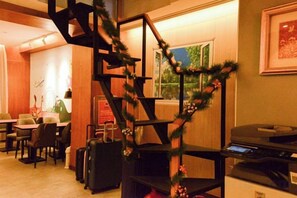 A hotel lobby with a staircase, seating area, and a desk with a computer. - Newful Hotel (Taipei)