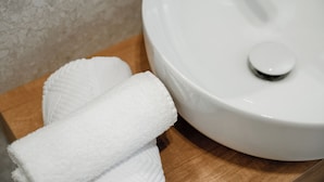 A white ceramic sink with a lid, a wooden countertop, and a white towel. - Riviera Suites Stanza 1 - by Be Your Home (Civitavecchia)