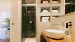 A modern bathroom with a glass-enclosed shower, a large white sink, and built-in towel shelves. - Riviera Suites Stanza 1 - by Be Your Home (Civitavecchia)