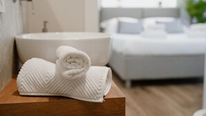 Une salle de bain avec un lavabo, une serviette et un lit en arrière-plan.