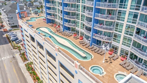 A hotel with multiple balconies, a pool area, and a parking lot. - Prince Resort Oceanfront 3BR Pools Lazy River (north myrtle beach)