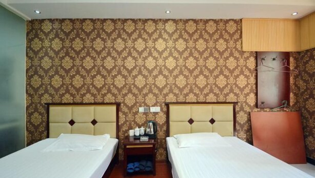 A hotel room with two beds, a nightstand, and a wall with a patterned wallpaper. - Quanjiao Jin'an Business Hotel (Quanjiao)