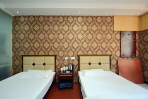Habitación de hotel con dos camas, una mesita de noche y una pared con papel tapiz estampado.
