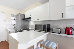 Enjoy cooking in this well-equipped kitchen with a stainless steel refrigerator, microwave, and toaster.