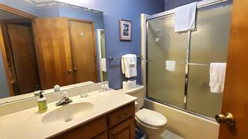 A bathroom with a sink, mirror, toilet, and a glass shower enclosure.