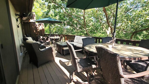 An outdoor deck with wicker furniture, a round table, and a green umbrella. - THREE BEDROOM,THREE BATH CONDO WITH HUGE DECK LOCATED ON THE ISLAND! (Holiday Island)