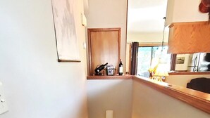 A staircase with wooden steps and handrails, leading to a room with a window and a door. - THREE BEDROOM,THREE BATH CONDO WITH HUGE DECK LOCATED ON THE ISLAND! (Holiday Island)