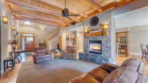 A spacious living room with a fireplace, leather sofas, and a staircase leading to another level. - Luxe All-season Retreat by Avantstay Prime Location, Near Skiing (Truckee)