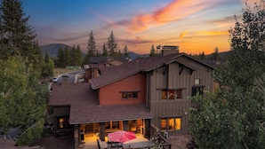 A modern two-story house with a patio area featuring outdoor furniture and a red umbrella. - Luxe All-season Retreat by Avantstay Prime Location, Near Skiing (Truckee)