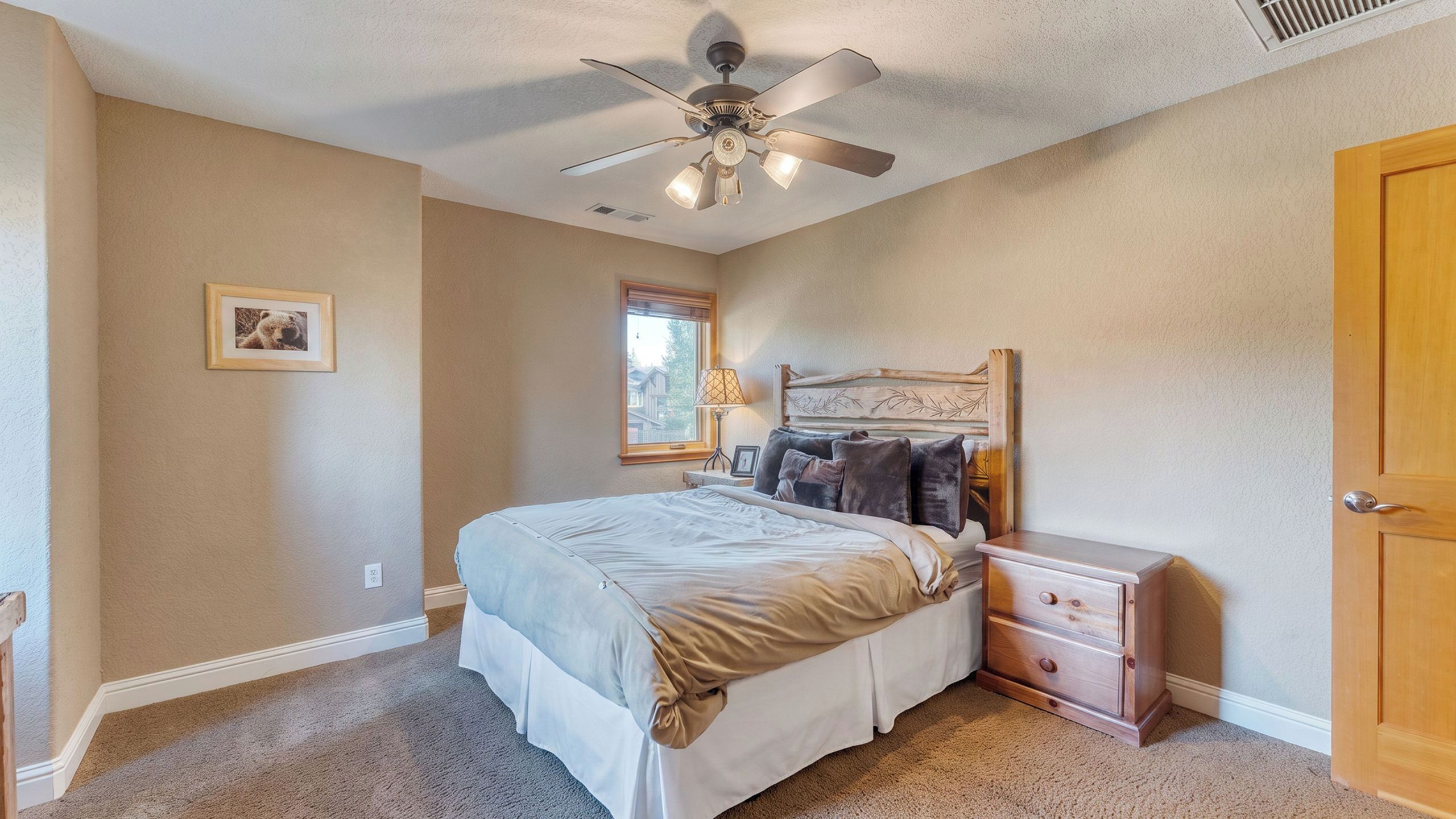 Une chambre à coucher avec un lit, une table de chevet, une lampe et un ventilateur de plafond.