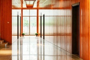 Un pasillo con piso pulido, paredes de madera y una puerta al final.