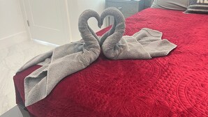 A bed with a red quilt, a heart-shaped towel arrangement, and a bedside table with a lamp. - Chic 1-bedroom apartment with AC, WiFi in fantastic Fort Myers (Fort Myers)