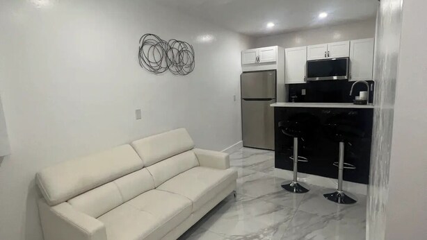 A modern kitchen with white cabinets, a stainless steel refrigerator, and a black microwave. - Chic 1-bedroom apartment with AC, WiFi in fantastic Fort Myers (Fort Myers)