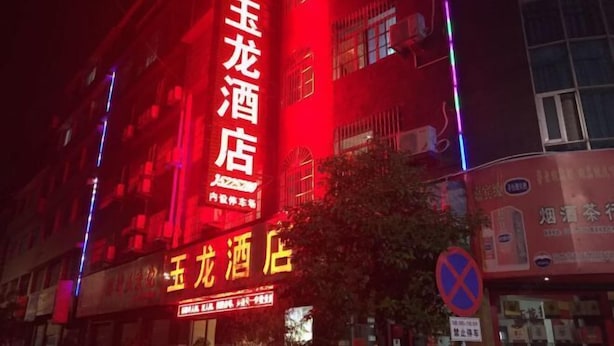Un hotel con un cartel rojo llamativo y un cartel amarillo más pequeño debajo.