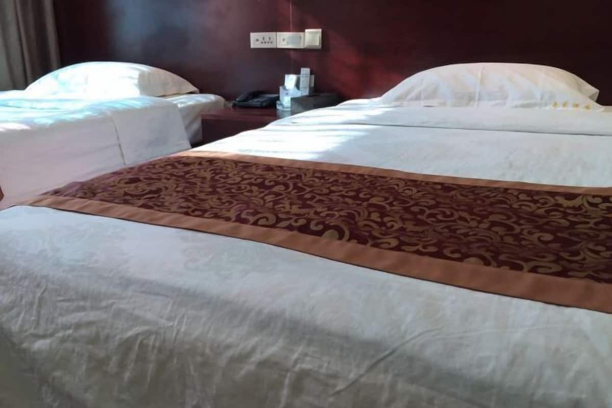 A hotel room with a large bed, two bedside tables, and a nightstand.