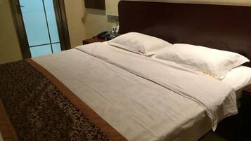 A neatly made bed with white linens and a brown patterned runner.