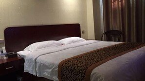 Una habitación de hotel con una cama, una silla y una mesita de noche con lámpara.