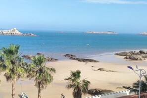 A beach with palm trees, a rocky shoreline, and a clear blue sky. - Yinghaiju Hotel, Weizhou Island (Putian)