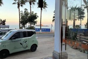 A parked car with a cartoon character design, a glass door entrance, and a view of the sea and palm trees. - Yinghaiju Hotel, Weizhou Island (Putian)