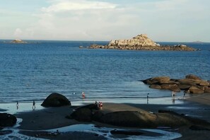A beach with large rocks, calm water, and a distant rocky island. - Yinghaiju Hotel, Weizhou Island (Putian)