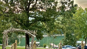 A wooden arbor structure in a park with a lake in the background. - Lakefront, hot tub, 2 bdrm w/ loft, kayaks, beach, fire pits,! sxs trails (La Follette)