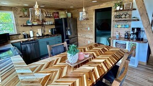 A modern kitchen with a large wooden table, built-in appliances, and pendant lighting. - Lakefront, hot tub, 2 bdrm w/ loft, kayaks, beach, fire pits,! sxs trails (La Follette)