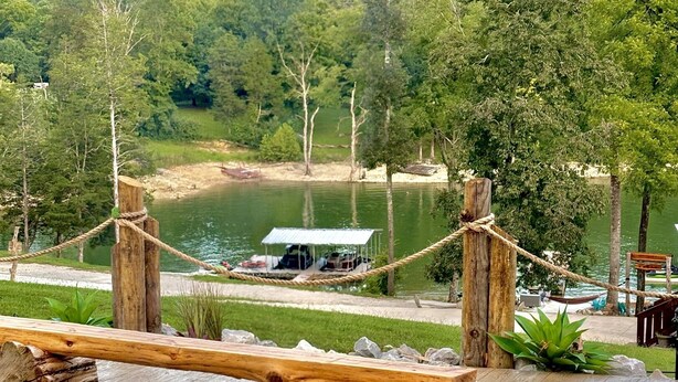 A fire pit with a view of a lake and a cabin in the background. - Lakefront, hot tub, 2 bdrm w/ loft, kayaks, beach, fire pits,! sxs trails (La Follette)