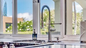 A modern kitchen with a stainless steel faucet, a soap dispenser, and a granite countertop. - Gorgeous Renovated Condo Walking Distance to Beaches!! Large Private Lanai (Kihei)