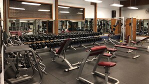 A gym with various exercise equipment, mirrors, and a large mirror reflecting the equipment.
