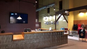 A reception desk with a computer, a flat-screen TV, and a clothing display.