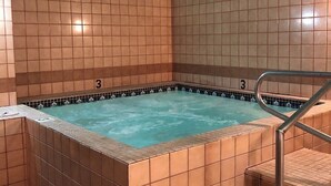 A hot tub with tiled walls and a metal staircase leading to it.
