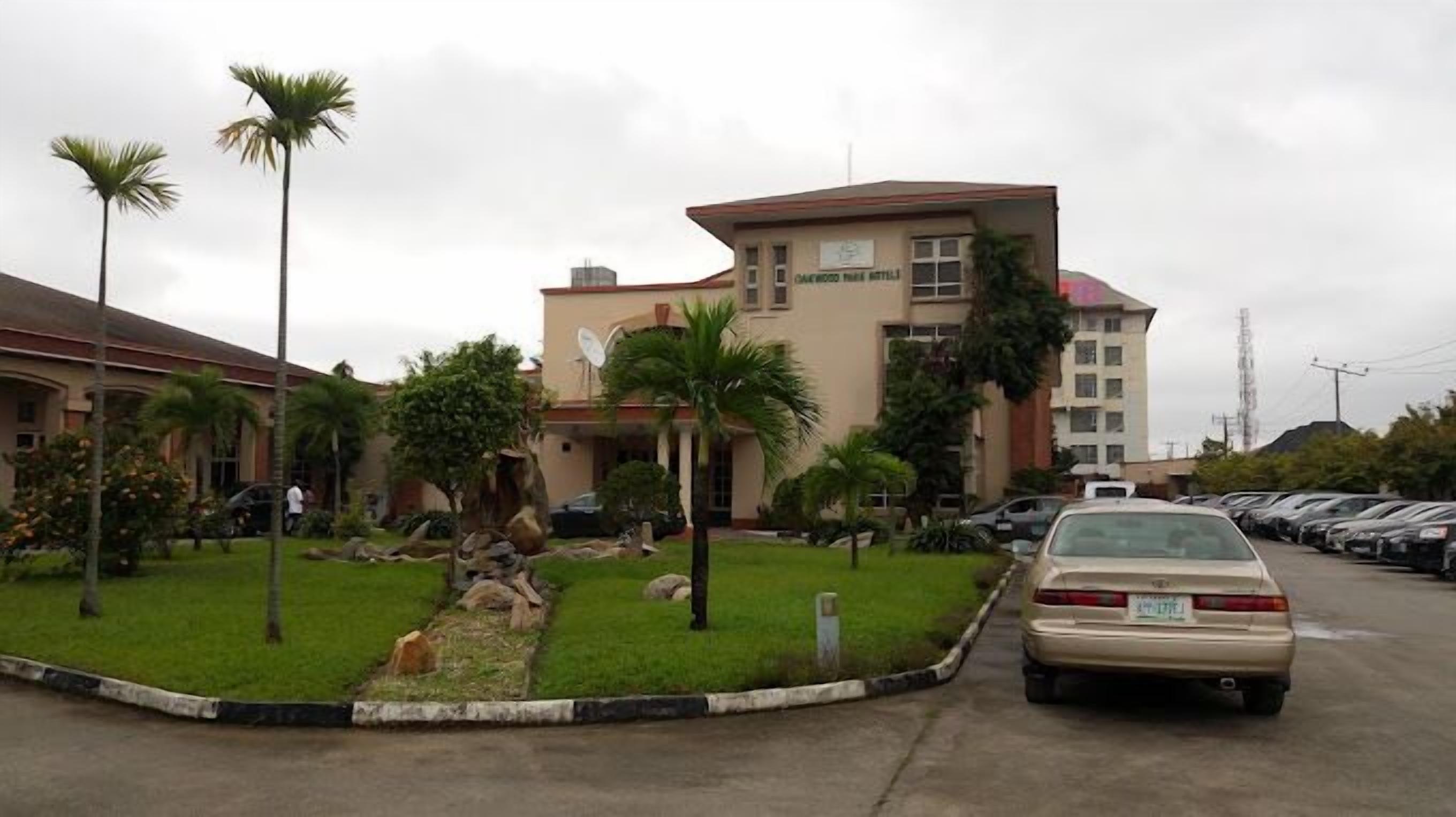 Un hotel con parcheggio, palme e un edificio con un cartello.