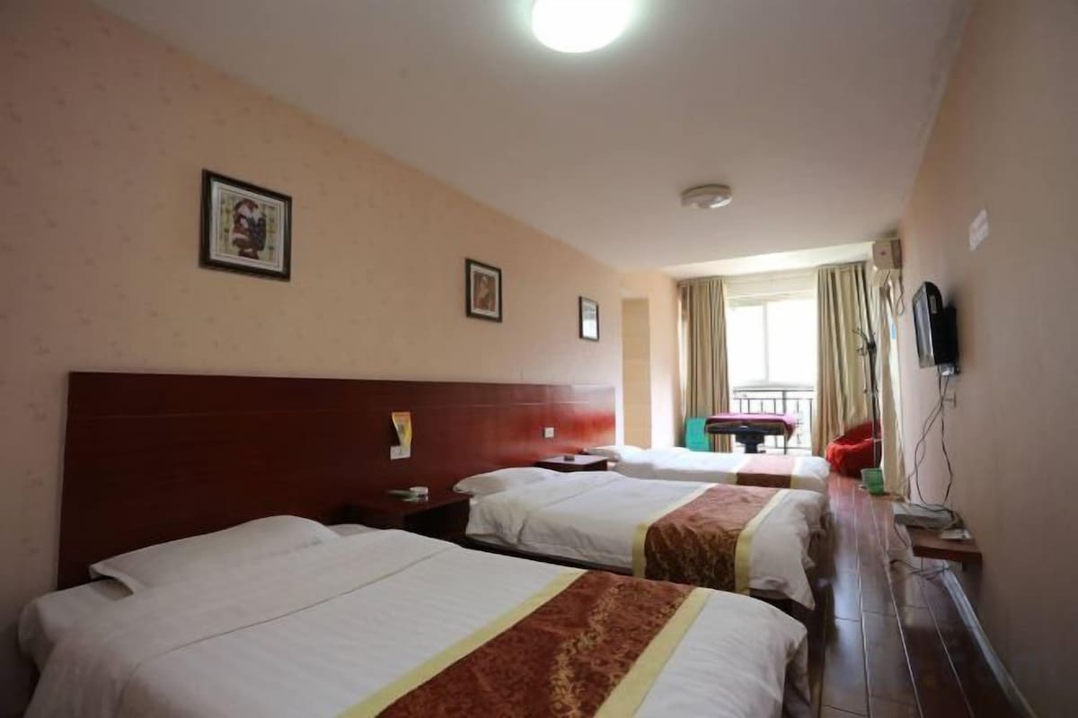 A hotel room with two beds, a desk, a chair, and a television.