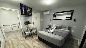 Een moderne slaapkamer met een bed, nachtkastje en een tv aan de muur waarop Netflix wordt weergegeven.