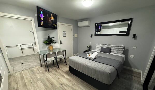 Un dormitorio moderno con cama, mesita de noche y televisor montado en la pared que muestra Netflix.