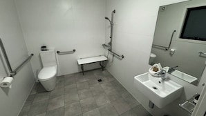 Een compacte, moderne badkamer met toilet, zitje, wastafel en douche.