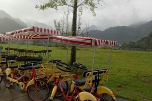 Una fila de bicicletas estáticas con sombrillas rojas y blancas a rayas, estacionadas sobre una superficie pavimentada.