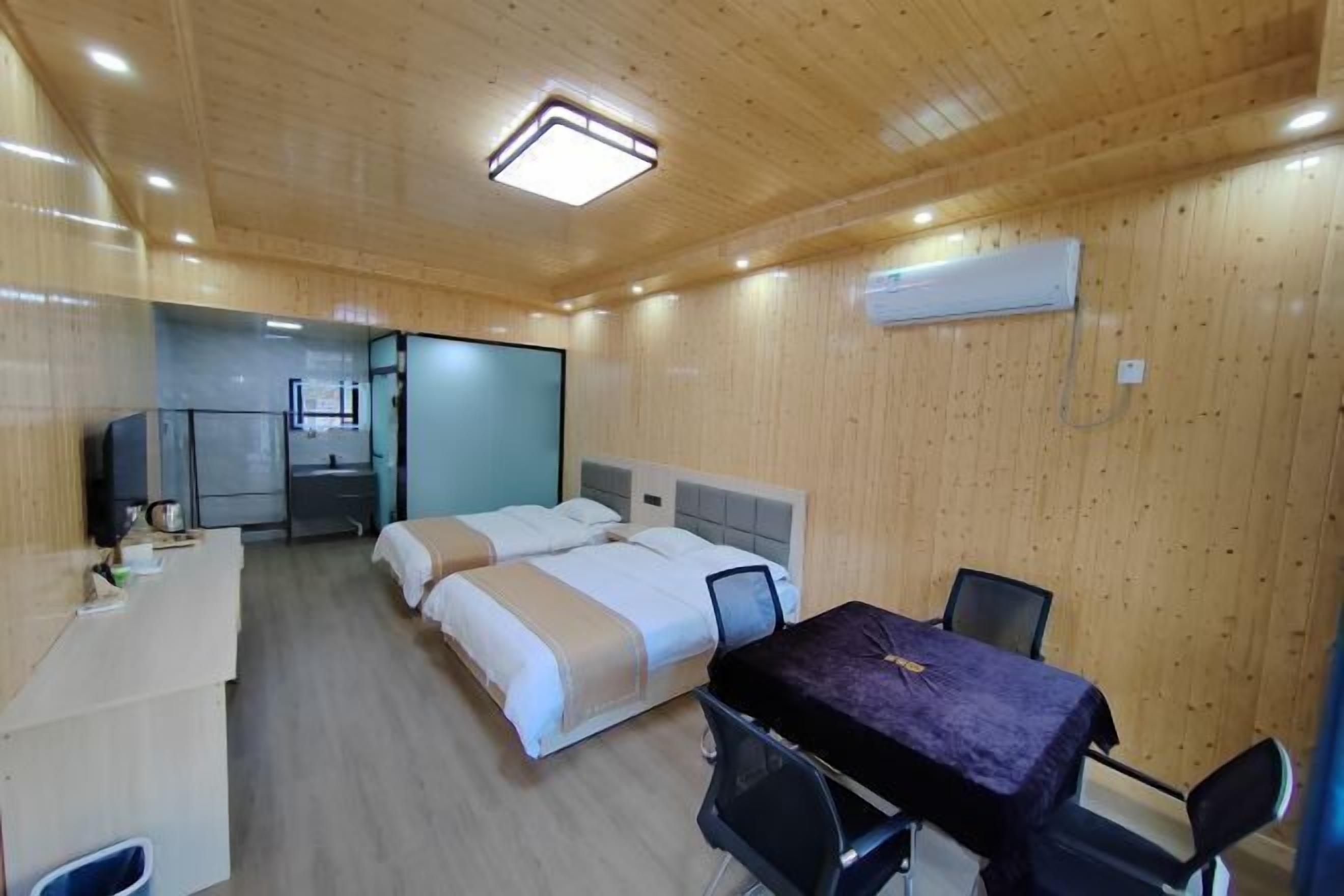 Een kamer met houten wanden, een bed, een bureau en een tafel met stoelen.