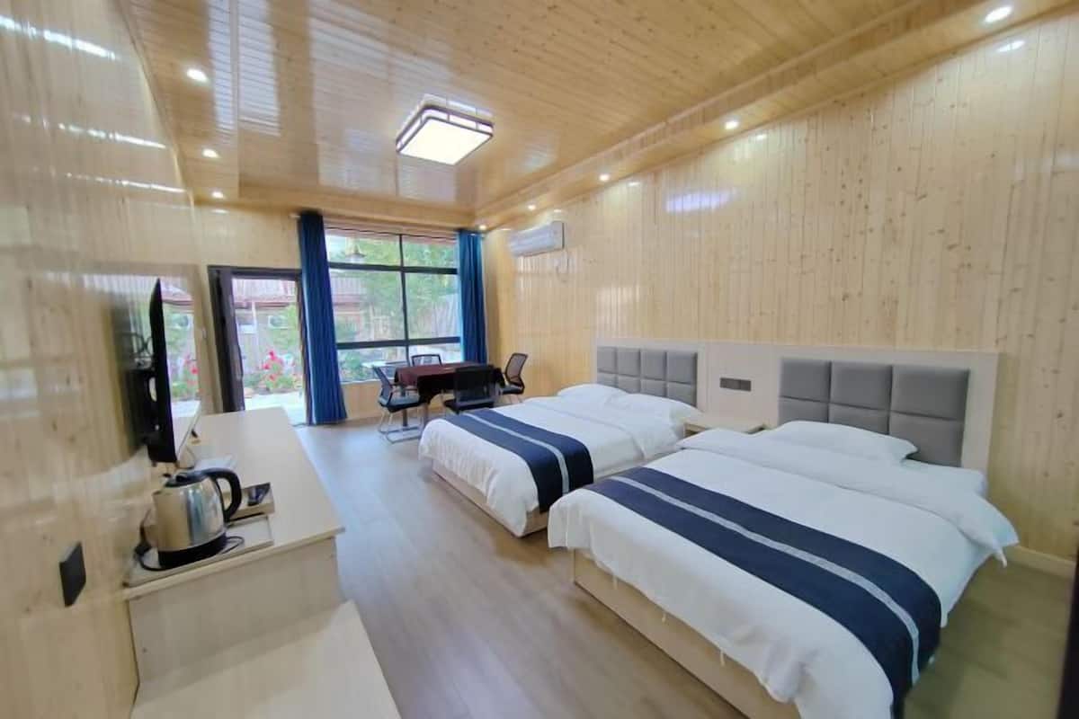Une chambre d’hôtel avec deux lits, un bureau avec une bouilloire et une télévision.