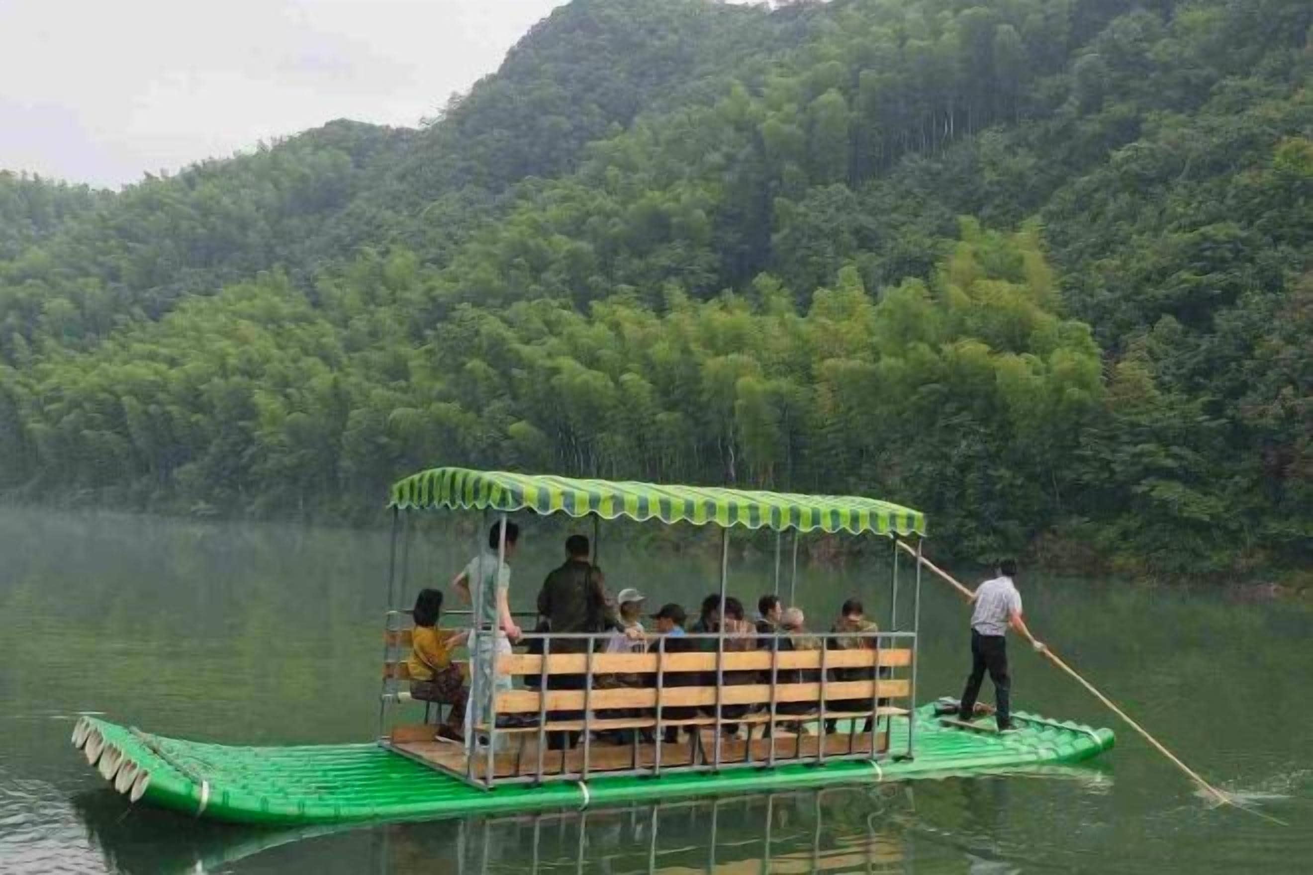 Un bote verde con zona de estar cubierta y una persona remando.