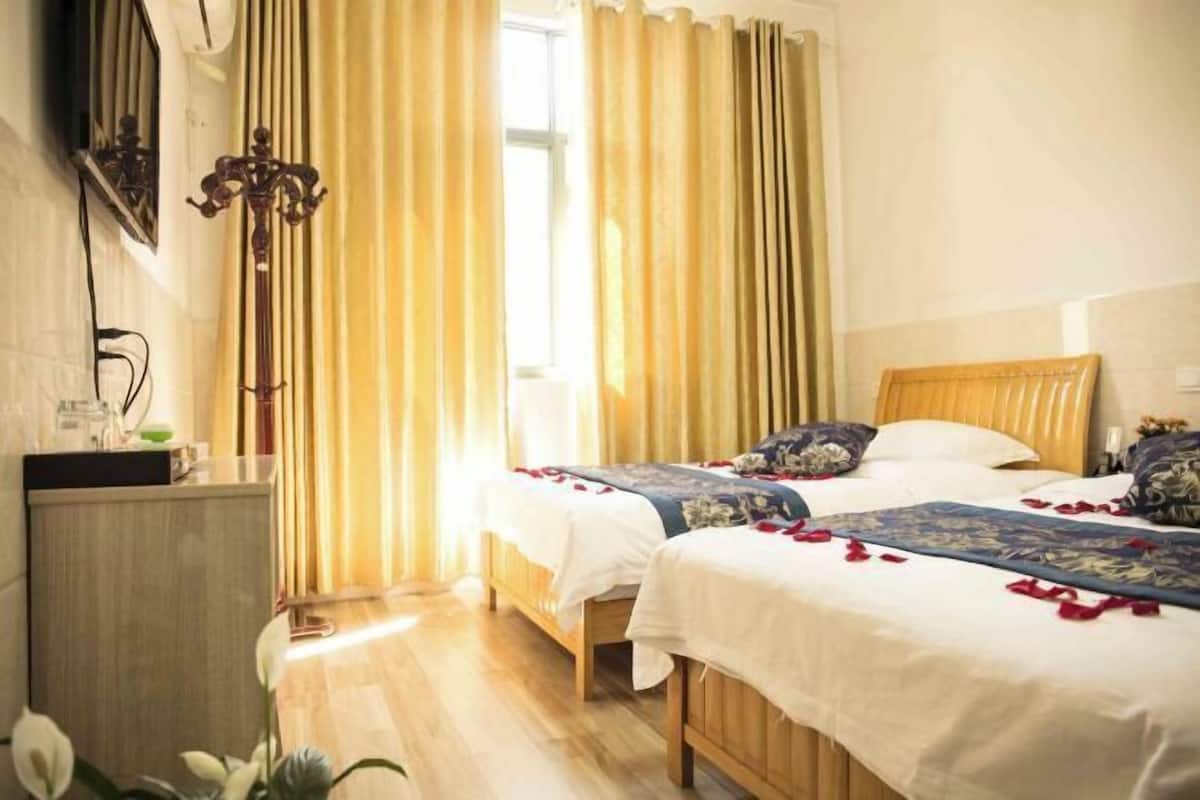 Une chambre d’hôtel avec deux lits, une tête de lit en bois, une table de chevet, un miroir et une fenêtre avec des rideaux.