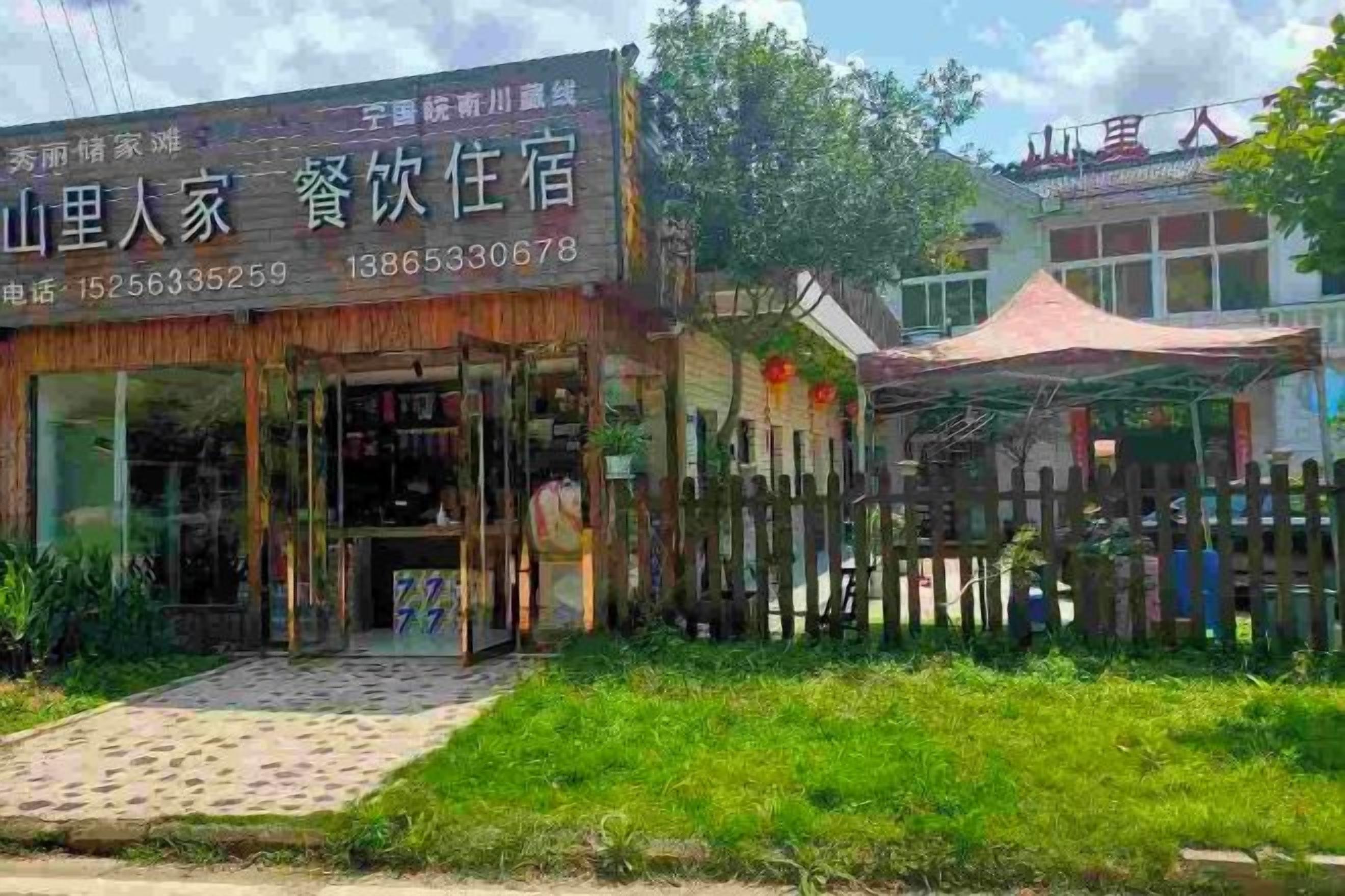 A hotel with a visible entrance, a fenced outdoor area, and a clear sky.