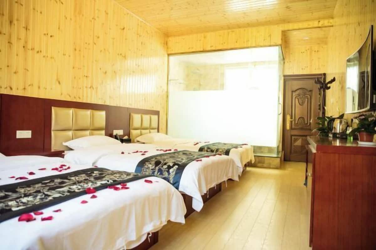 Une chambre d’hôtel avec des murs en bois, une grande fenêtre, une tête de lit en bois et un lit recouvert d’une courtepointe à motifs floraux.