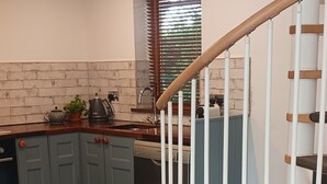 Une cuisine moderne avec des meubles gris, un escalier en bois et un canapé gris.