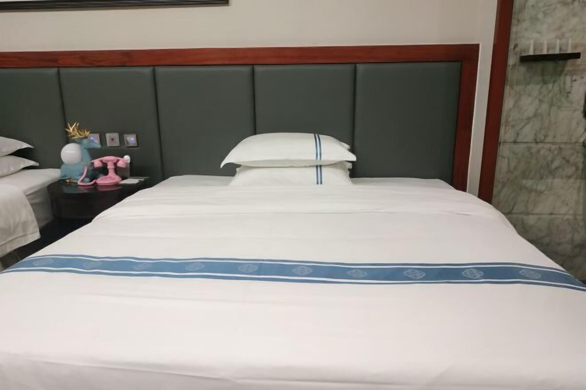 A hotel room with a large bed, a nightstand with a lamp, and a decorative item on the nightstand.