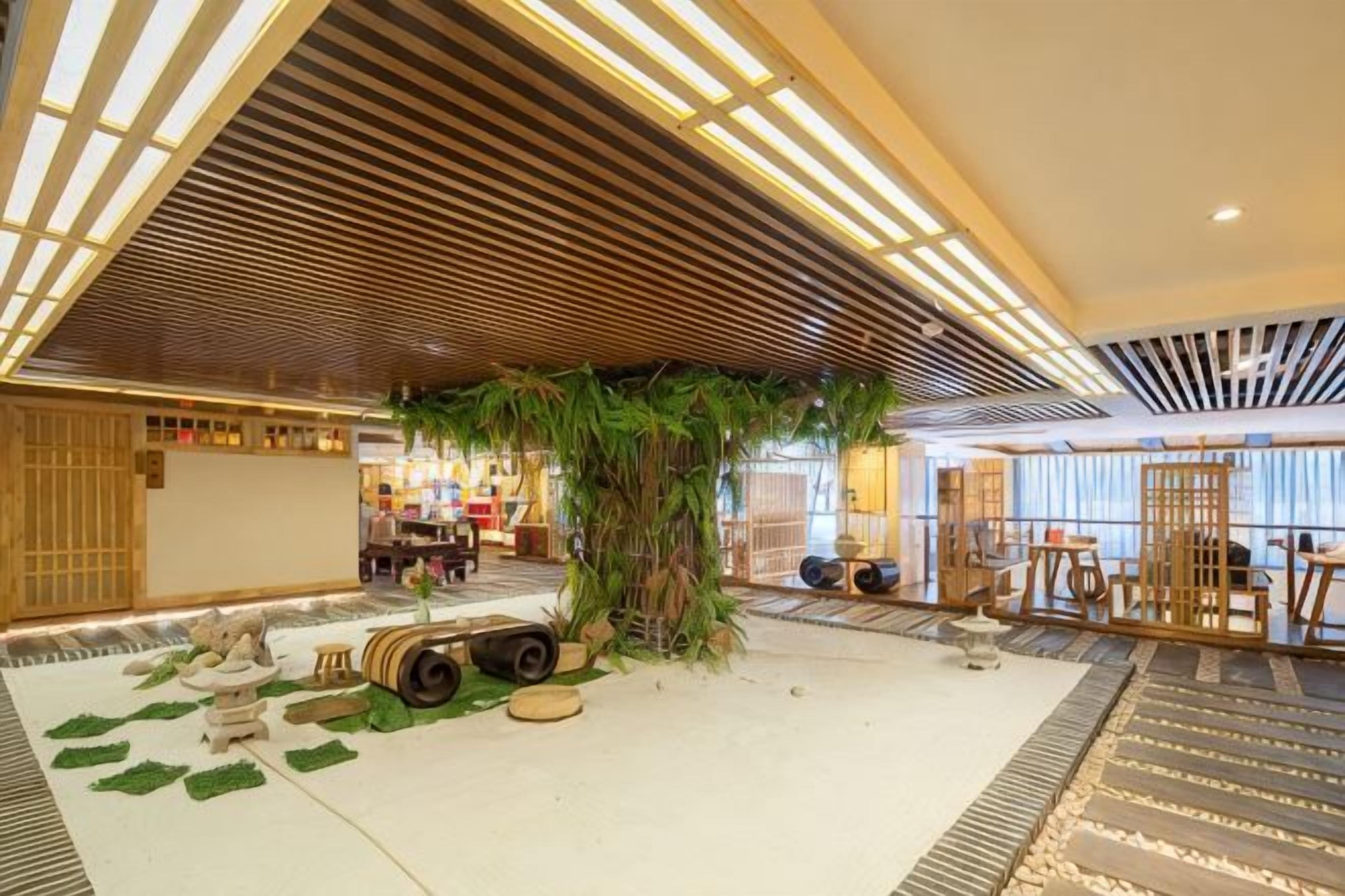 A spacious lobby with a large indoor plant, seating areas, and a reception desk.